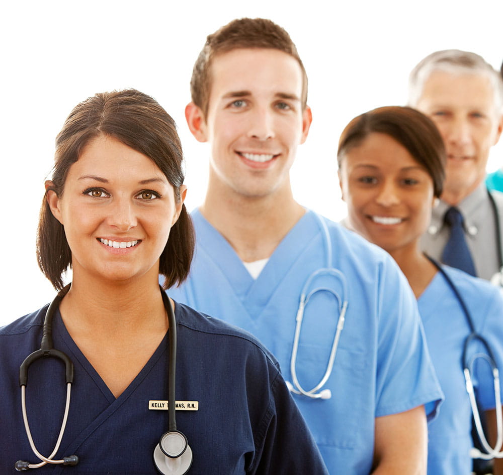 Four healthcare workers standing in a line with a female doctor at the front, then a male doctor, female doctor and male doctor at the back