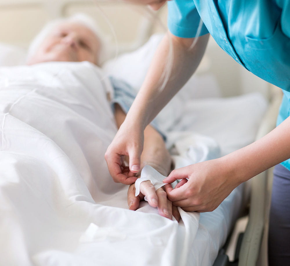 Healthcare worker adjusting a plaster on a patient lying in a hospital be