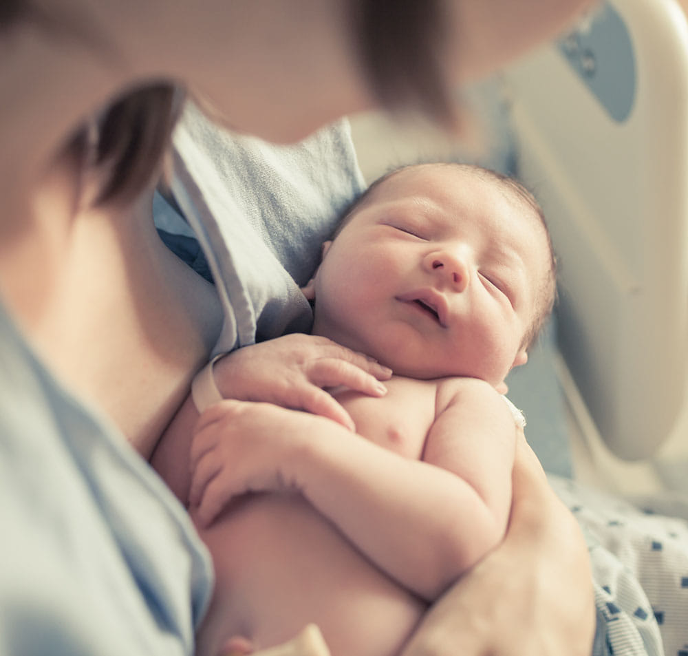 Newborn baby sleeping in the arms of a healthcare professional