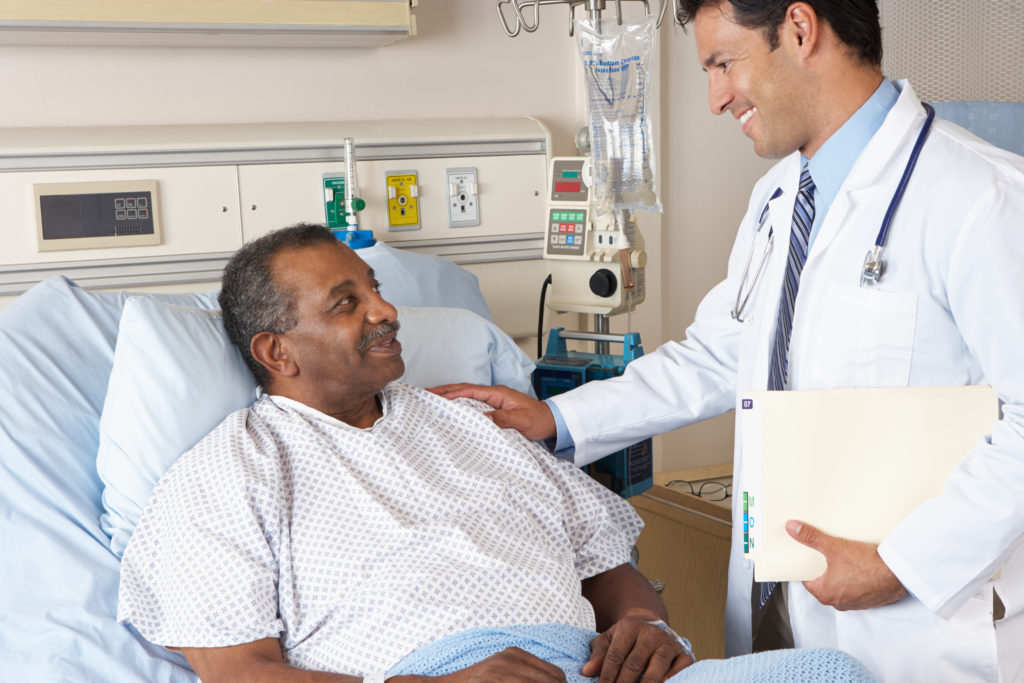 Man in hospital bed speaking to a doctor
