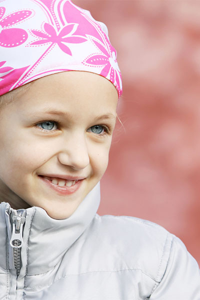 Young girl with cancer wearing a white and pink headscarf